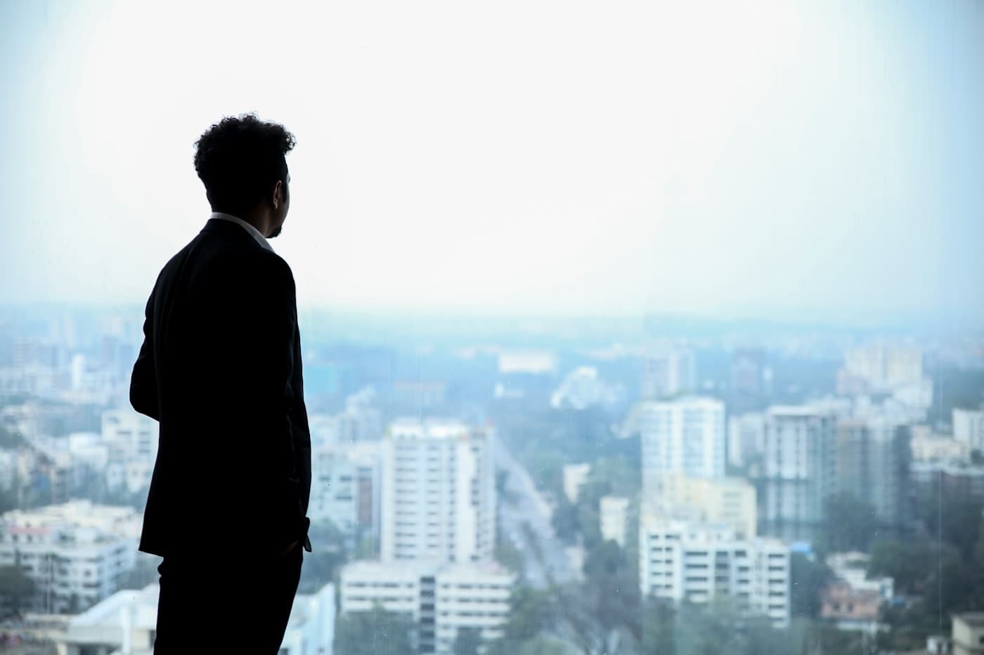Un homme en costume, de dos, observant la ville